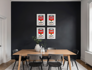 Four Andy Warhol Campbell's Soup fine art prints displayed in a grid formation on a dark wall in a modern dining room.